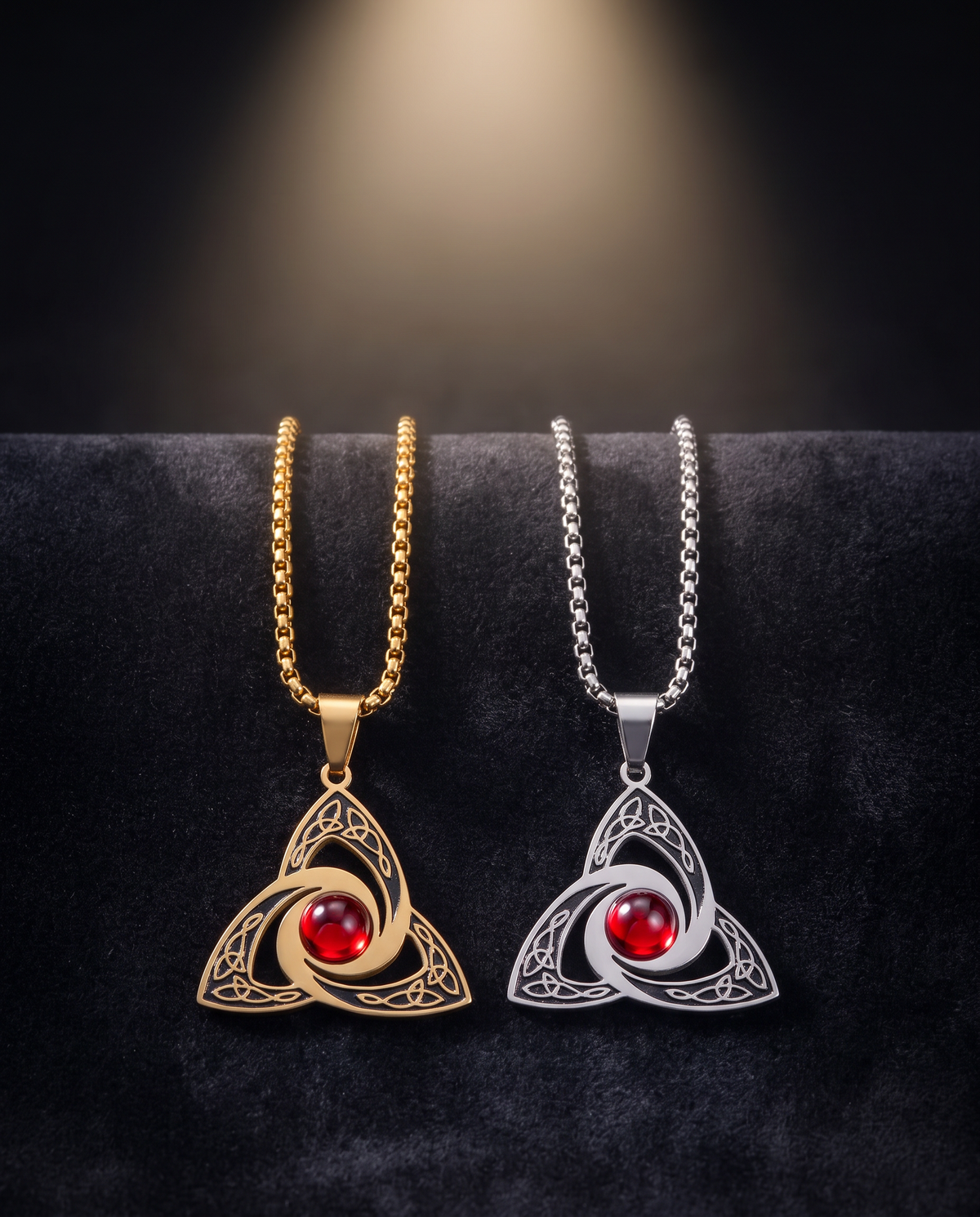 Gold and silver trinity knot necklaces on dark velvet under a spotlight
