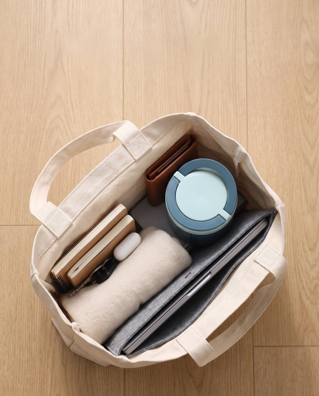 Lunch jar packed in a tote bag with a laptop, notebook and sweater