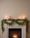 Cedar garland with warm fairy lights along a white fireplace mantel