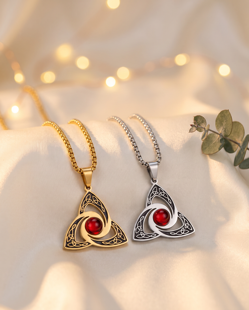 Gold and silver Celtic trinity knot necklaces with red crystal on ivory satin